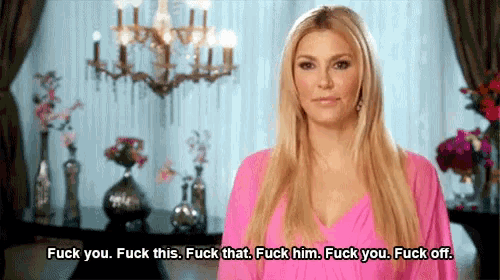 a woman in a pink dress is standing in front of a chandelier .