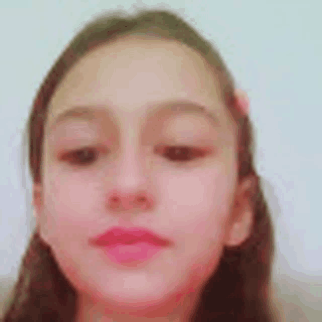 a close up of a young girl 's face with a pink lip gloss on her lips .
