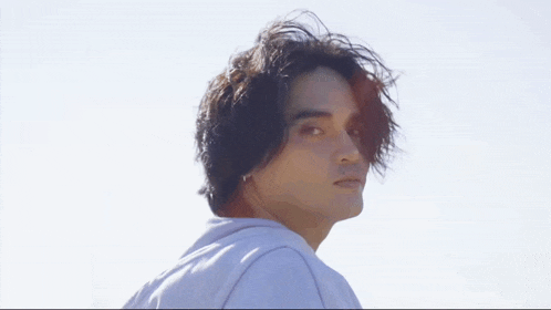 a young man with long hair is wearing a white sweatshirt