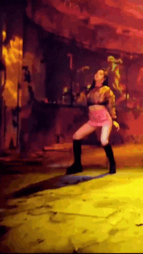 a woman in a pink skirt is dancing on a stage in a dark room .