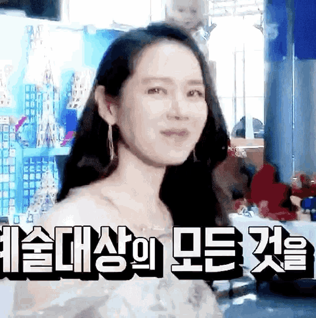 a woman in a white dress is smiling and looking at the camera in a room with korean writing on the wall .