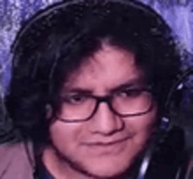 a young man wearing glasses and headphones is smiling .