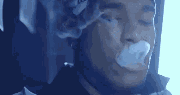 a man is smoking a cigarette with smoke coming out of his mouth and nose .