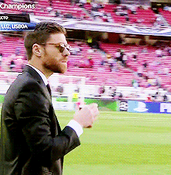 a man in a suit stands on a soccer field with a sign that says champions