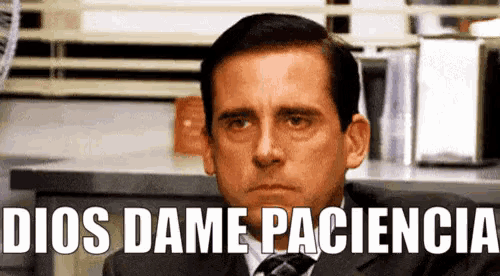 a man in a suit and tie is sitting in front of a sign that reads dios dame paciencia