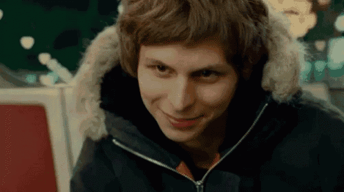 a young man wearing a black jacket with a fur hood smiles .