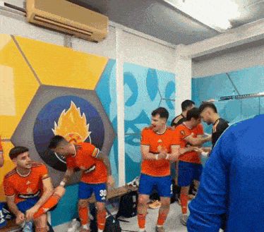 a group of soccer players are in a locker room with a mural on the wall