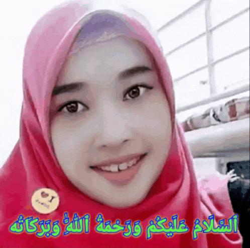 a woman wearing a pink hijab is smiling with arabic writing on the bottom