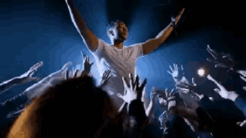 a man is standing in front of a crowd of people with his arms in the air .