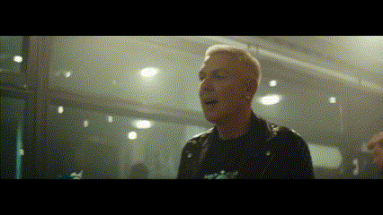 a man in a leather jacket is standing in a dark room .