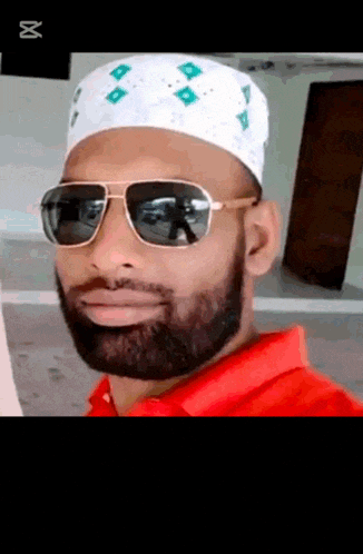 a man with a beard wearing sunglasses and a white hat .