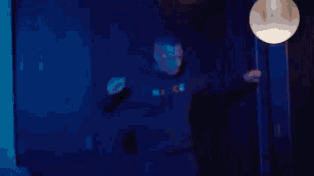 a person is walking down a hallway in a dark room with blue lights .