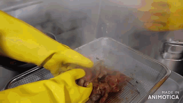 a person wearing yellow gloves is putting a piece of meat in a container that says made in animatica
