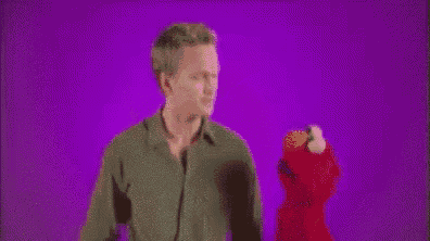 a man is standing next to a stuffed animal , elmo .