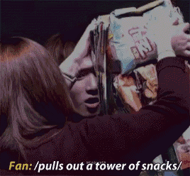 a woman pulls out a tower of snacks from a box
