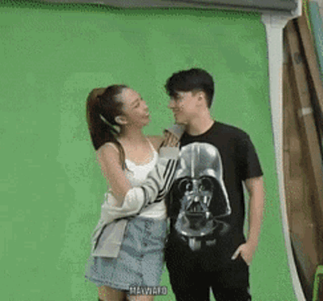 a man wearing a darth vader shirt is standing next to a woman .