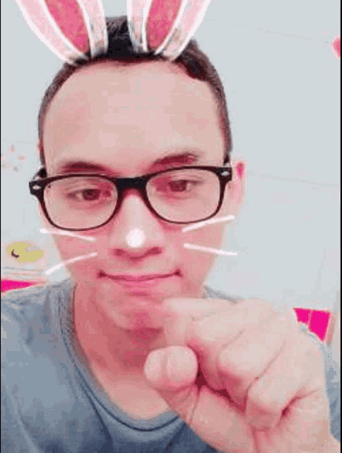 a man wearing glasses and bunny ears is making a heart shape with his finger .