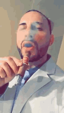 a man in a suit is smoking a cigar with a blue smoke coming out of his mouth .