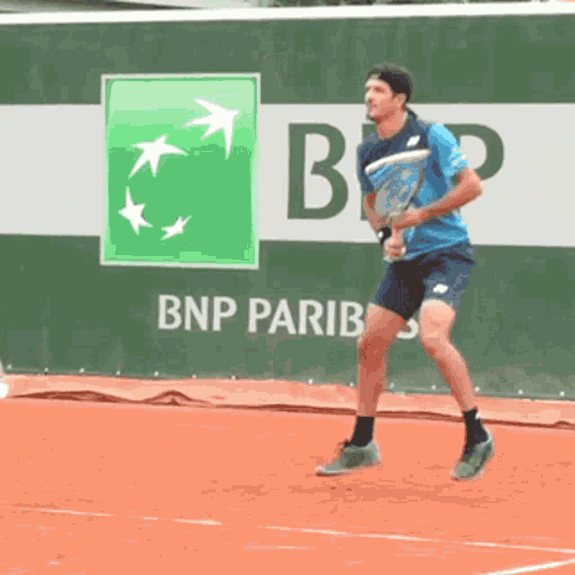 a man is playing tennis in front of a bnp pariba ad