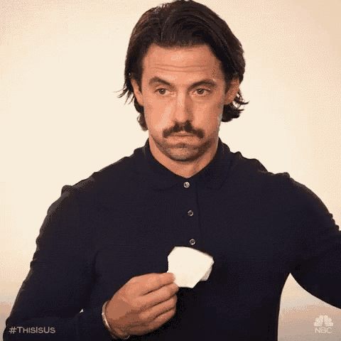 a man with a mustache is holding a piece of paper to his face .
