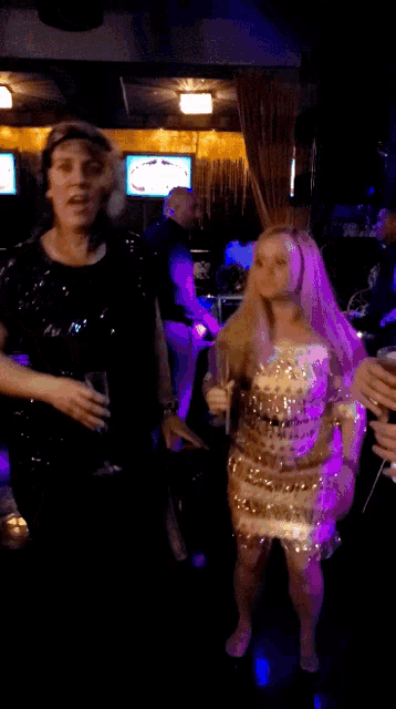a woman in a sequined dress is dancing with a man in a black shirt