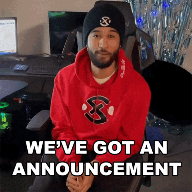a man in a red hoodie is sitting in a chair with the words we 've got an announcement behind him