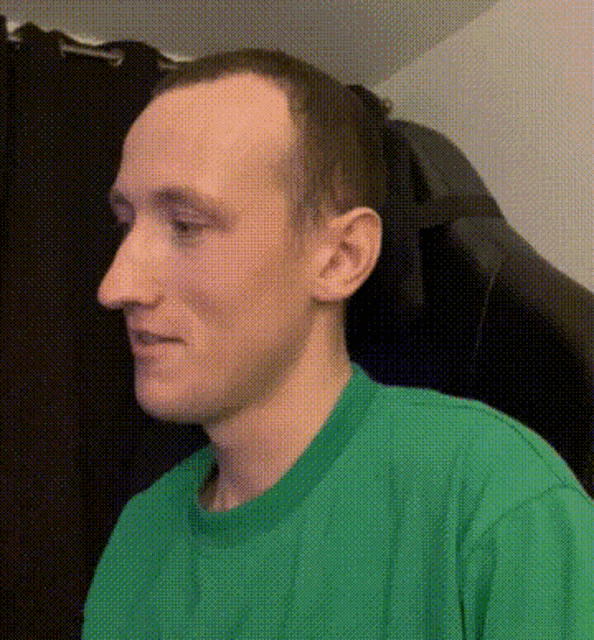 a man wearing a green shirt is looking to his left