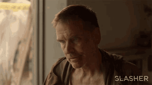 a man is sitting in front of a window with the word slasher on the bottom right