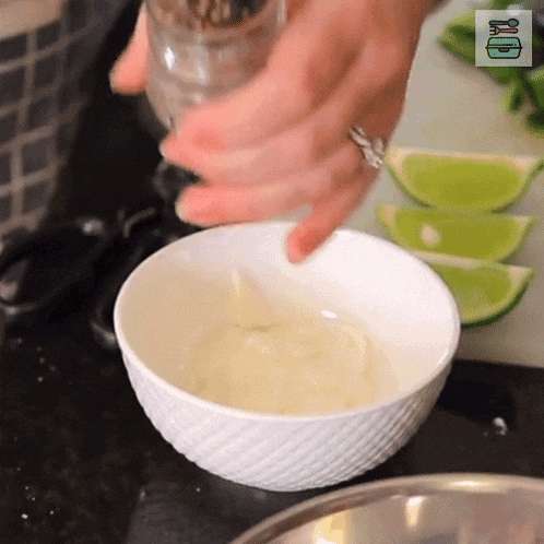 a person is using a salt and pepper shaker in a bowl