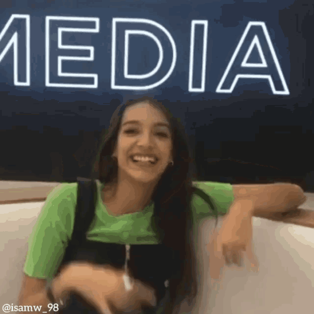 a girl is sitting in front of a sign that says media