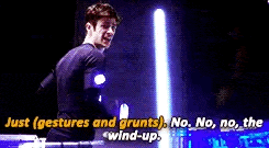 a man is standing in front of a light saber with the words `` just gestures and grunts '' written above him .