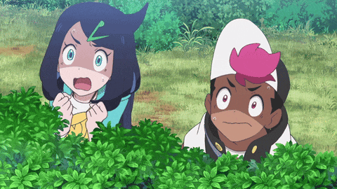 a boy and a girl are hiding behind a bush in a field