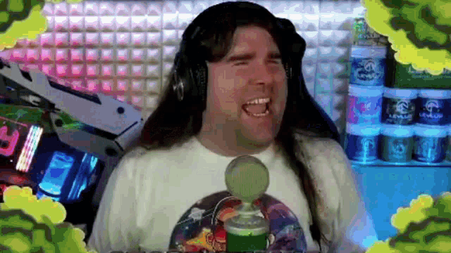 a man with long hair is wearing headphones and laughing in front of a microphone
