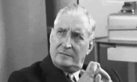 a black and white photo of a man in a suit and tie making a face .