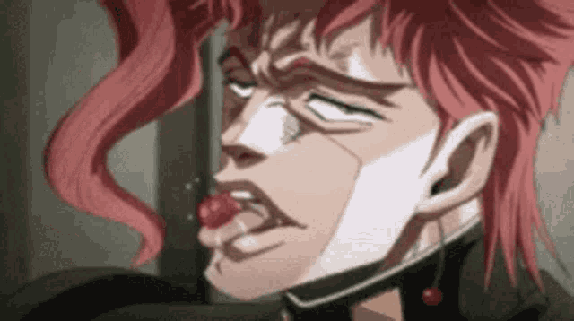 a man with red hair is eating a cherry with his tongue out .