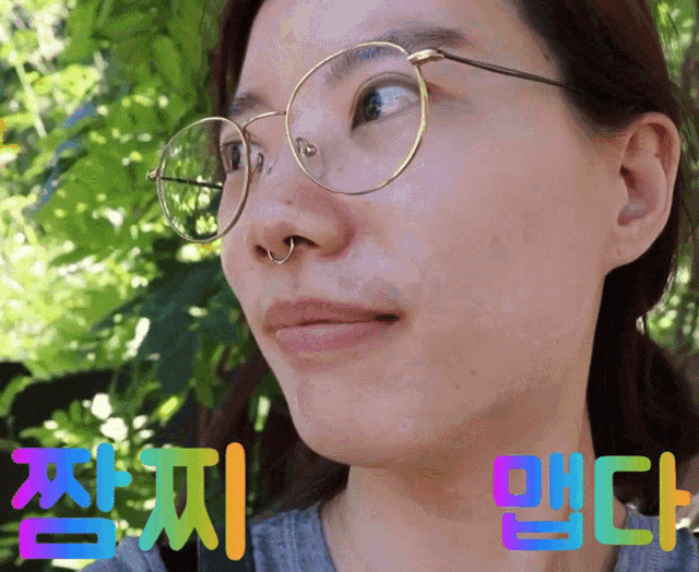 a woman wearing glasses and a nose ring is surrounded by colorful letters in korean