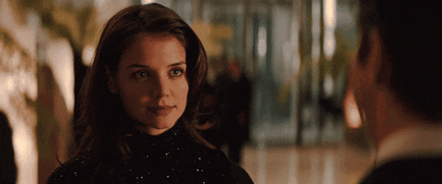 a woman in a black dress looks at a man
