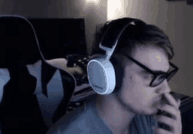 a man wearing headphones and glasses is sitting in a chair in a dark room .