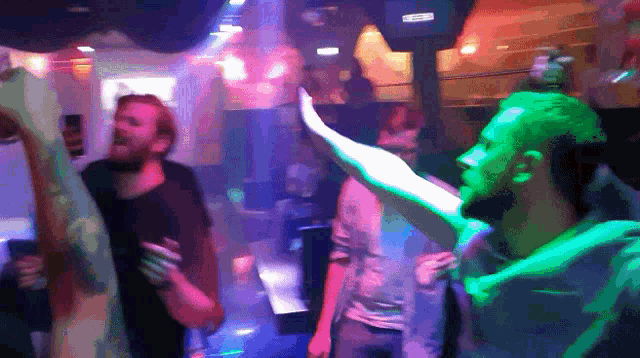 a group of people are dancing in a dark room with a sign on the wall that says ' eee ' on it