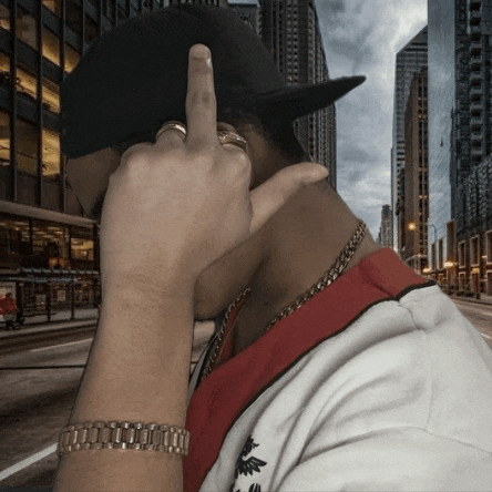 a man wearing a hat and a watch is giving the middle finger