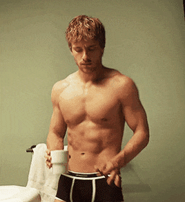 a shirtless man holding a cup of coffee