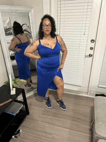 a woman standing in front of a mirror wearing a blue dress and sneakers