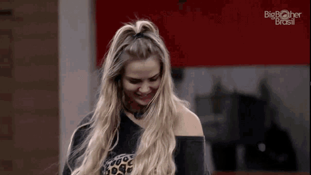 a woman with long blonde hair is wearing a black shirt with a leopard print on the front .