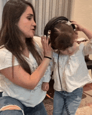 a little girl wearing headphones while a woman holds her head