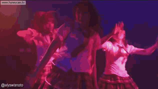 a group of girls in school uniforms are dancing on a stage while holding microphones .