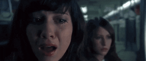 a woman is crying while another woman looks on while riding a subway .