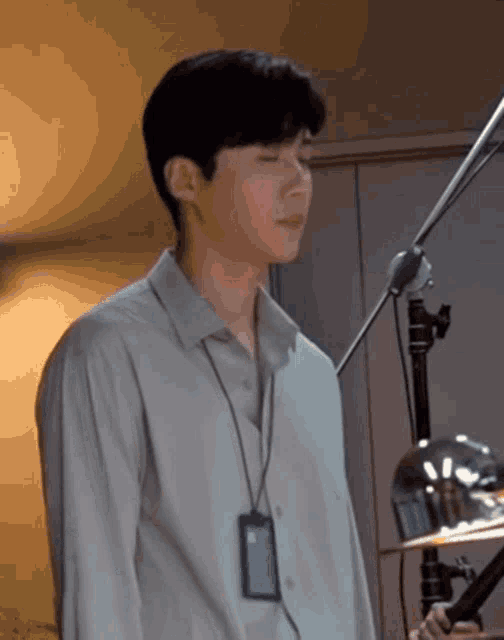 a young man is standing in front of a microphone with his eyes closed .