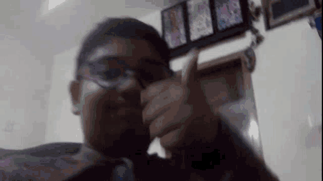 a man wearing glasses is giving a thumbs up sign .