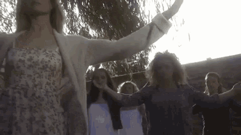 a group of women are standing in a circle holding hands and dancing .