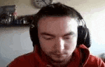 a man wearing headphones and a red shirt is looking down .
